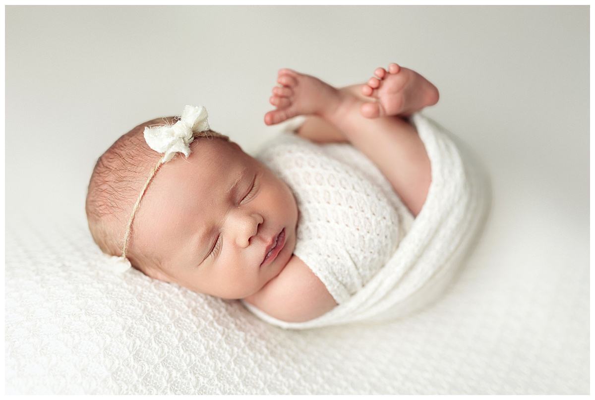 tiny toes stick out of swaddle while little one sleeps by Amy Yang Photography