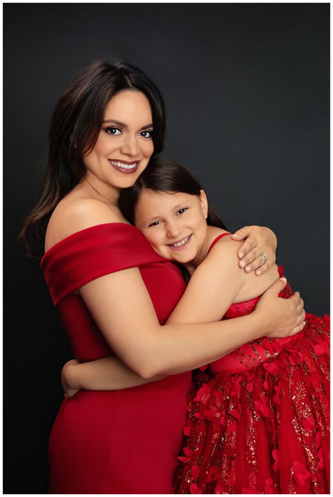 mom hugs daughter in matching red dresses by Charlottesville luxury photographer