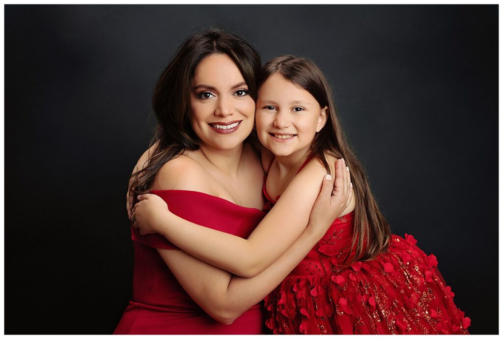 mother and daughter hug in red dresses during women's portrait session