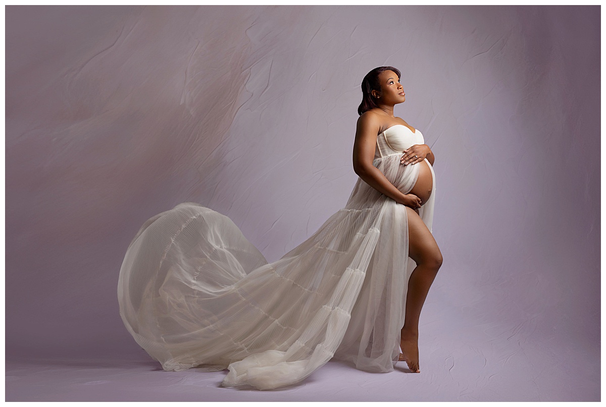 mother-to-be holds her growing belly and looks up during legacy maternity session