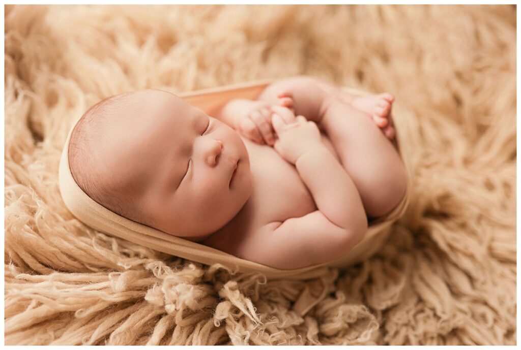 swaddled babe lays on shaggy rug at baby boy studio session 