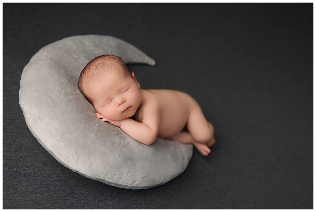 newborn rests head on moon pillow at baby boy studio session