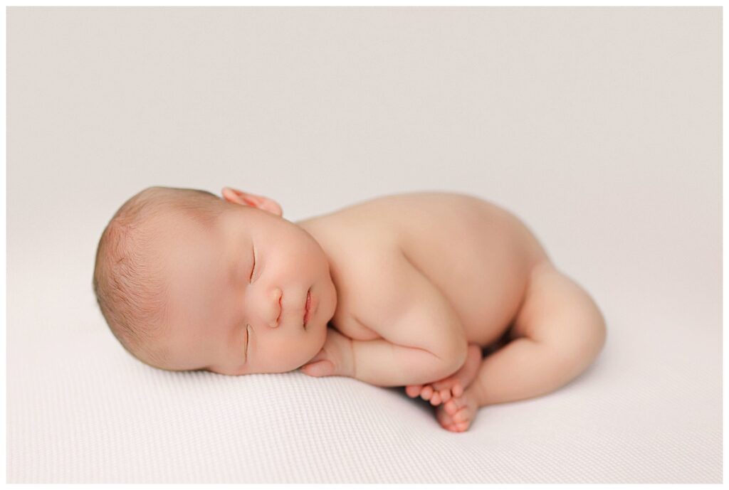 sleeping infant rests on white blanket by Amy Yang Photography