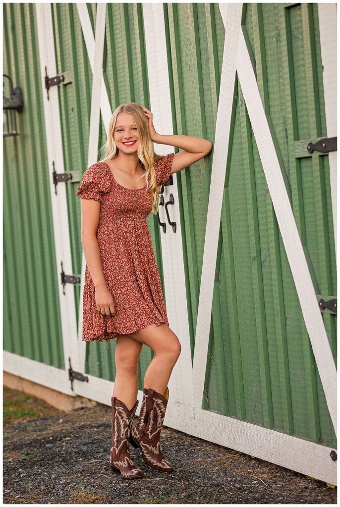 girl leans elbow against stable during senior session